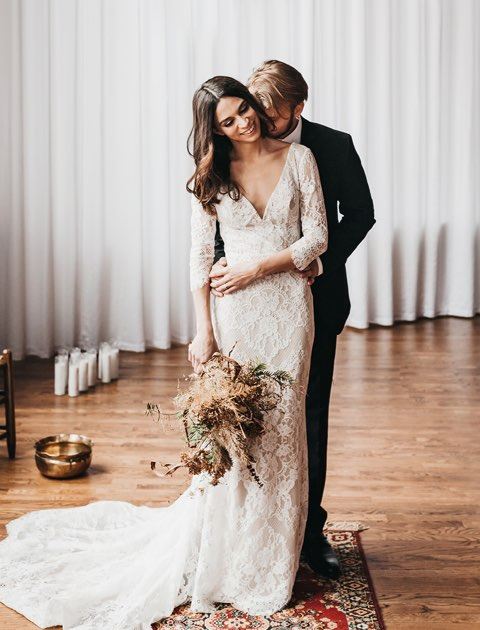 Groom hugs brunette bride from behind at the studio